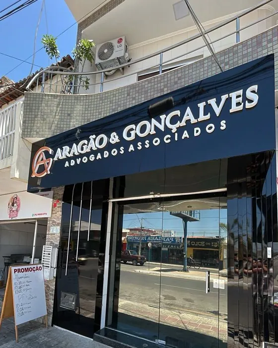 Fachada do escritório na Av. Adolfo Viana, com o letreiro azul-marinho Aragão & Gonçalves e portas de vidro